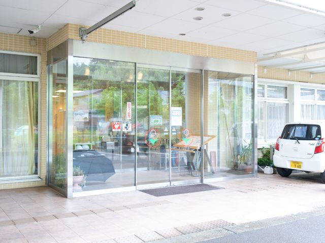 明るいエントランス風景 玄関 ゆったりとしたエントランスは、訪れる方々を明るい雰囲気で迎えます。ガラス越しに見える車椅子も、バリアフリーへの配慮が感じられます。