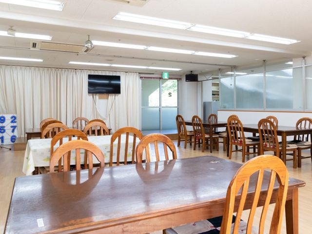 共有スペースのダイニング 食堂 天井が高く開放的なダイニングルームです。明るく広々としたこの空間で、みなさんが和やかに食事を楽しまれています。
