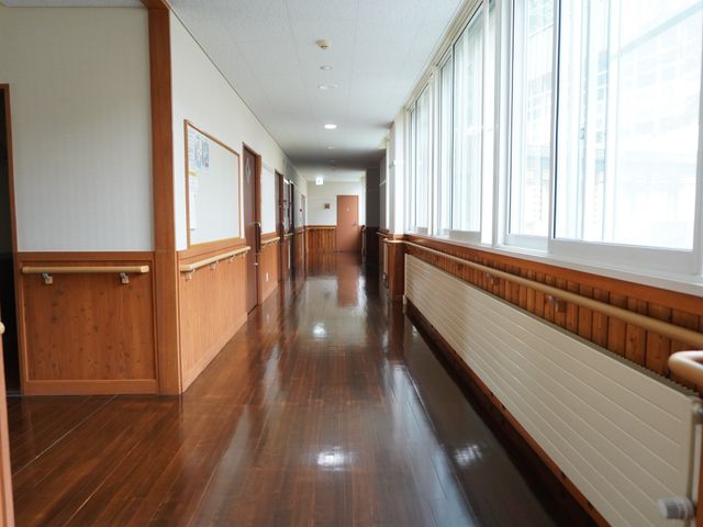 広々とした明るい廊下 廊下 手すりが設置された廊下はゆったりとしており、安心して歩行できる設計です。木目調で温かみのある空間が広がっています。