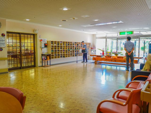 明るいロビー空間 エントランス 広々としたロビーには、入口近くに鮮やかな花が飾られ、利用者や訪問者の方々が心地よく時を過ごしています。