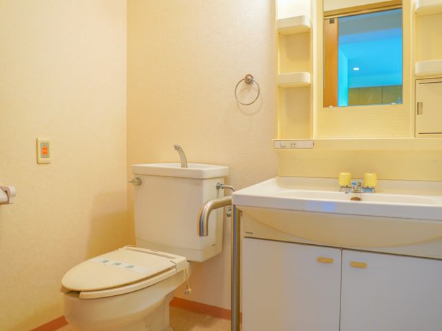 清潔なトイレと洗面台 トイレ 手すりが設置された清潔なトイレ空間です。快適にご利用いただけるよう配慮されています。