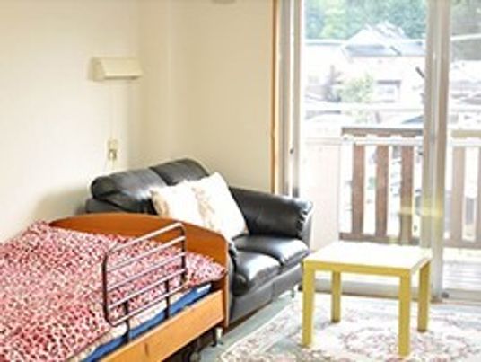 施設の写真 ベッドやソファが置かれた居室にはバルコニーもつき、外の空気を楽しむことができる。