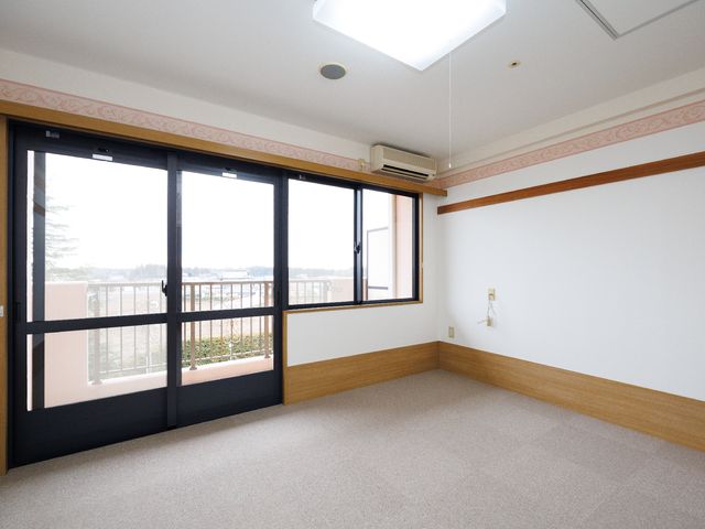 明るい洋室とベランダ 居室 広々として明るい居室からは、ベランダ越しに穏やかな景色が望めます。清潔感があり、ゆったりとした時間を過ごせる空間です。