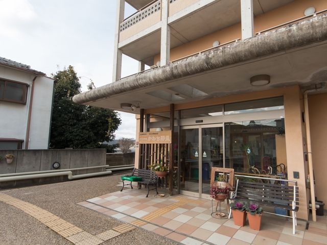 広々とした入口エリア 玄関 ゆったりとしたエントランスには、明るい光が差し込み、来訪者を暖かく迎えています。ベンチにご用意された植物も空間に彩りを添えています。