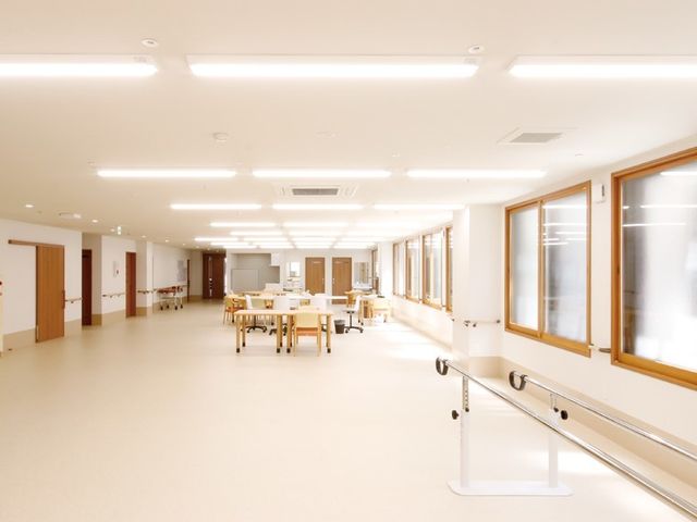 広々とした明るい廊下 機能訓練スペース 広々とした通路は落ち着いた色合いで、ゆとりのある空間設計が行われています。安全に配慮した手すりが設置され、皆さまの快適な移動を支えます。