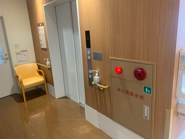 木目調の廊下 廊下   木目調で落ち着いた廊下です。椅子や手すりがあり、移動しやすい工夫が見られます。