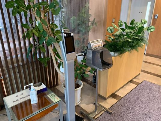 受付前の自動検温機と消毒台  