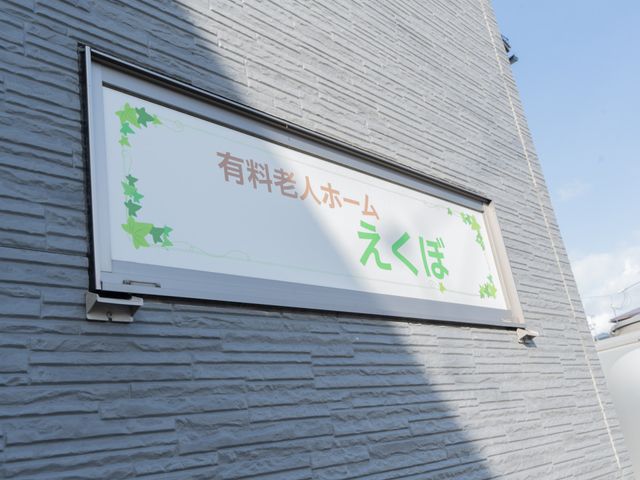 施設の看板 看板 青空の下、施設名が書かれた看板が建物の外壁に設置されています。