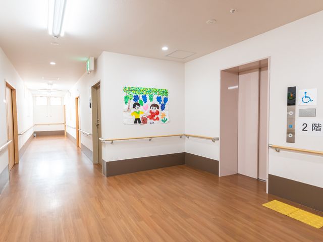 広々とした施設の廊下 エレベーター ゆったりとした廊下が、職員と利用者の円滑な移動を支えています。手すりが整っており、どなたでも安心してご利用いただける造りです。