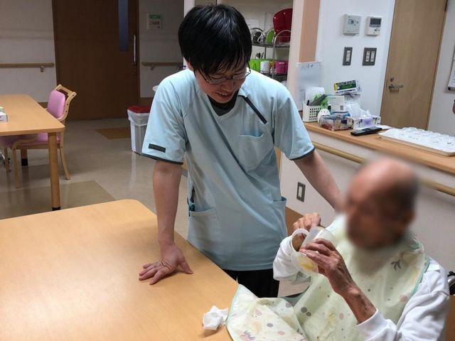 スタッフと利用者の様子 食堂 介護スタッフが優しく利用者のお手伝いをしています。明るい空間で安心して過ごせます。