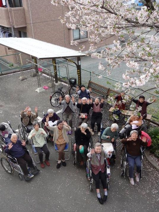 桜の下で手を振る人々