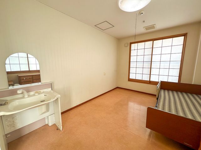 ゆったりとした居室 居室 暖かみのある床材と趣のある窓が特徴の、落ち着いた雰囲気の個室です。必要な備品も整っており、快適な生活空間を提供しています。