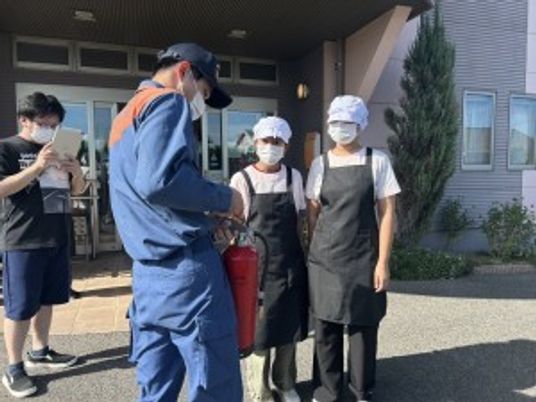 スタッフが屋外で消火器確認する様子  