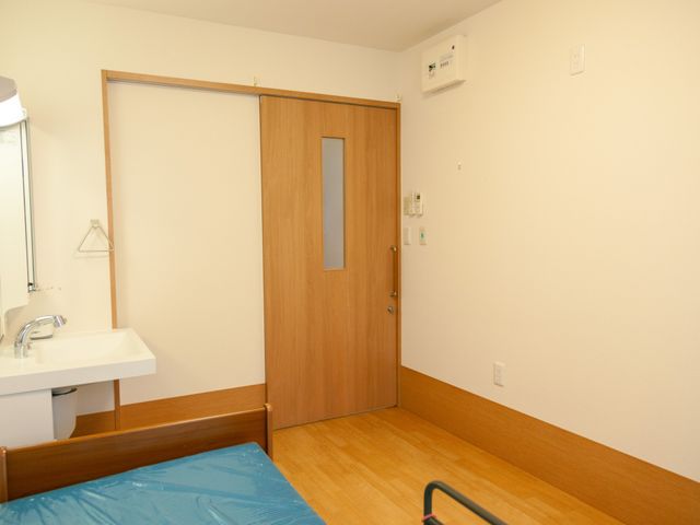 居心地のよい居室 居室 清潔感あふれる居室には、必要な設備が整い、落ち着いた色合いでまとめられています。手すり付きベッドや洗面台もご用意しており、快適にお過ごしいただけます。