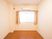 洋室の居室には腰窓があり、その上部にはエアコンが取りつけられている。室内の壁は白色で、床は明るい茶色の木目である。