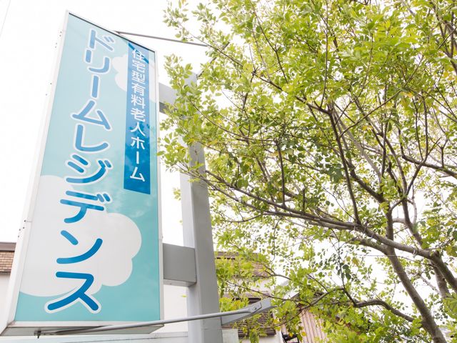 緑に囲まれた看板 外観 新緑がまぶしい季節に映える、施設の明るく親しみやすい看板です。ここでのお仕事は、自然に囲まれながらのやりがいを感じられるかもしれません。