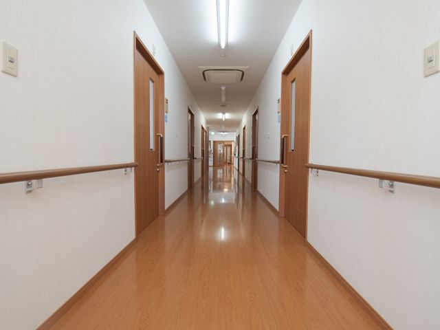 清潔で広い廊下 廊下 床が光沢を放つ、手すりの付いた廊下で、利用者の移動がしやすい設計になっています。手すりを利用しながらの歩行がスムーズにできるよう配慮されています。