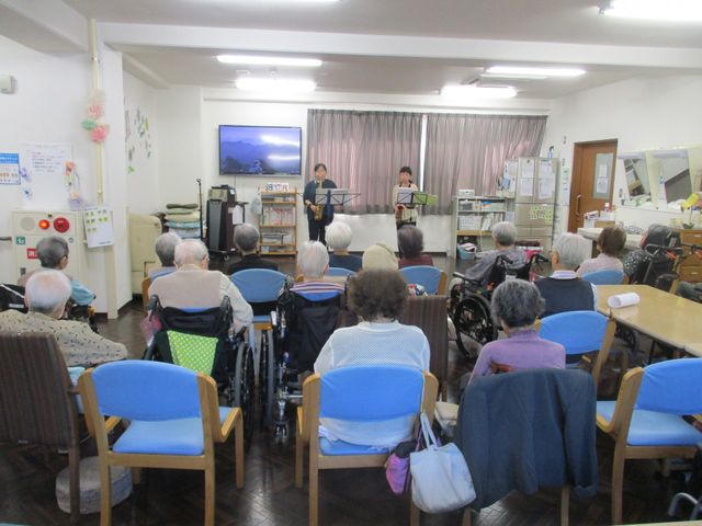 音楽を楽しむ食堂 食堂   広い食堂で、利用者の方々が席に座り、演奏を聞いています。車椅子でも過ごしやすい、ゆったりした空間です。
