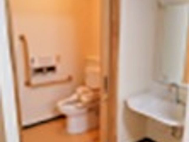 明るいトイレの内観 ゆとりある空間のトイレは清潔感があり、手すりも設置されて安心です。利用者の日々の快適さを考えた設備となっています。
