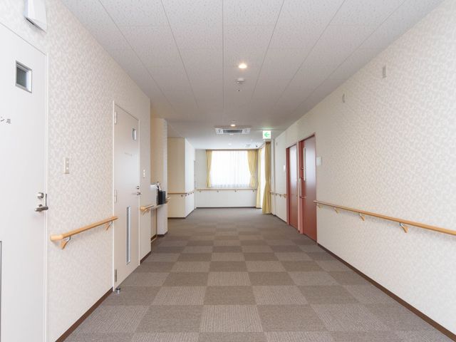 清潔感のある明るい廊下 通路 ゆったりとした廊下は壁に手すりが設置され、歩行時のサポートになっています。明るく暖かみのある空間で、安全に移動ができる環境です。