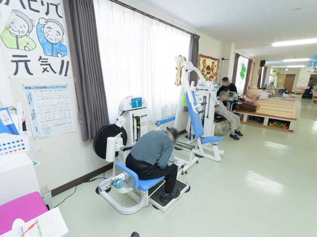 機能訓練室の様子 リハビリスペース 広々とした訓練室で、専門的機器を使用したリハビリテーションが実施されております。利用者の方々が健やかな毎日を過ごすためのサポートが充実しています。