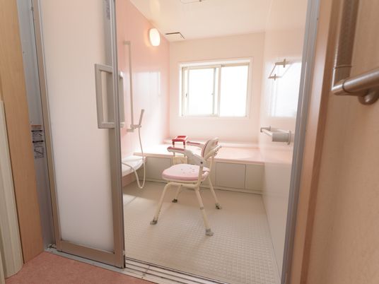 浴室はスライドドアで段差のない設計になっている。壁には手すりがついていて、シャワー椅子も置かれている。