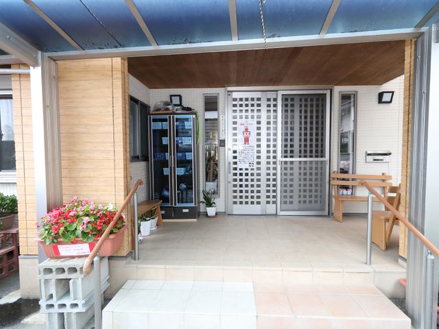 エントランスの静かな風景 玄関 木のぬくもりを感じる落ち着いたエントランス。植物が彩りを添え、訪れる方々を温かく迎えています。