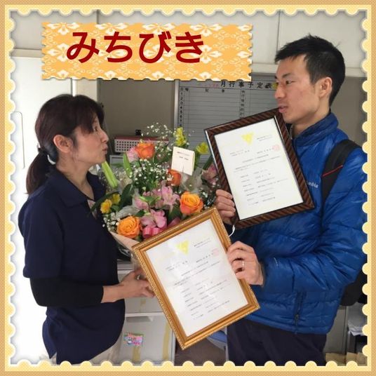 人物が花と賞状を持つ場面
