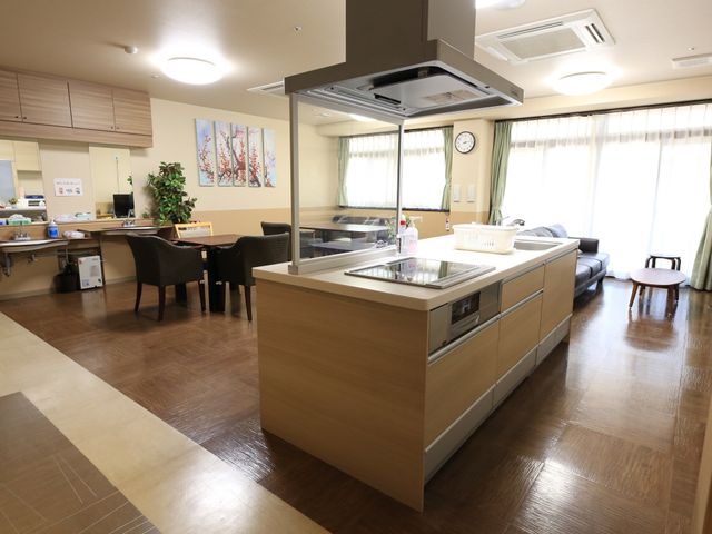 快適な共有スペース キッチン 落ち着いた色合いのダイニングスペースでは、共に食事をしながらゆったりと交流が図れます。車椅子でも安心の広々とした通路が確保されており、心地よいレイアウトが魅力です。