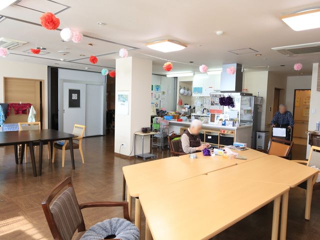 明るい食堂と利用者 食堂 日差しが降り注ぐ食堂では、利用者の方々が日々の食事や交流を楽しんでいます。ゆったりとした配置のテーブルや椅子が配置され、温かな雰囲気が感じられます。