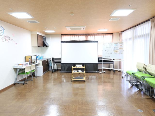 多機能スペースの様子 共有スペース ゆとりある広さのある多目的室です。プレゼンテーションや映画鑑賞などができる大型スクリーンと白板が備え付けられ、集会やレクリエーションに最適です。
