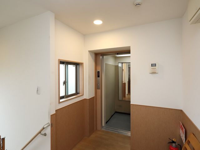廊下と入り口のイメージ エレベーター 明るく清潔な廊下は、手すりが設置され、安全に配慮された空間です。動線が考えられた設計で、ご利用者様の快適な移動が支援されています。