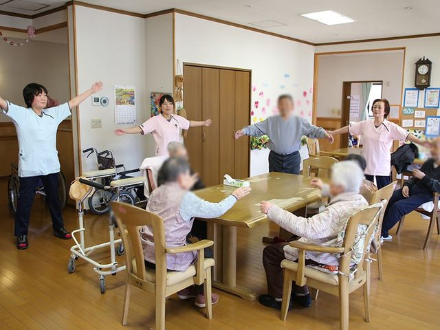 体操をする集団の部屋 多目的室 広々としたスペースで、スタッフと利用者が一緒に体操を行っています。楽しい雰囲気の空間です。