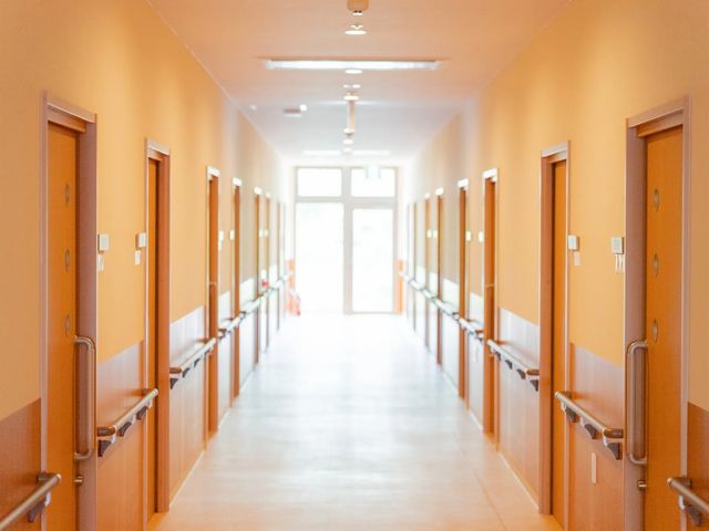 明るい廊下 廊下   両側に手すりと居室の扉が並ぶ、見通しのよい廊下です。奥から自然光が入り、歩きやすさが伝わります。