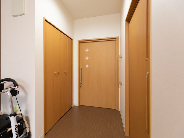 廊下と部屋の木製扉 居室 すっきりと整頓された廊下は床材も明るく、安心して歩行できる工夫がされています。扉は開閉しやすいデザインです。