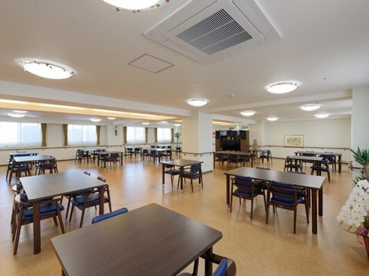 施設内の食堂兼リビングの空間。広めの空間に四人掛けのテーブルと椅子が並べられている様子