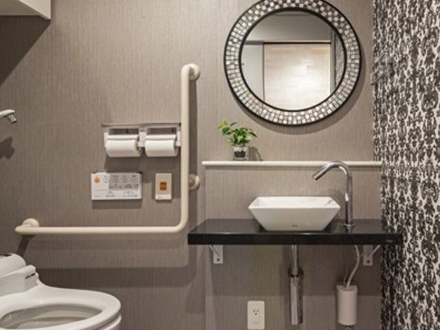 バリアフリートイレ 設備 手すり完備で安全性を考慮した清潔なトイレです。モダンなデザインが施された壁と床が高級感を演出しています。