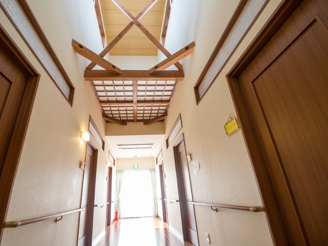 木造調の洗練された廊下 廊下 高い天井と木の温もりが感じられる廊下は、ゆとりある空間での就業が可能です。手すりが整備され、歩行に安心感を提供します。