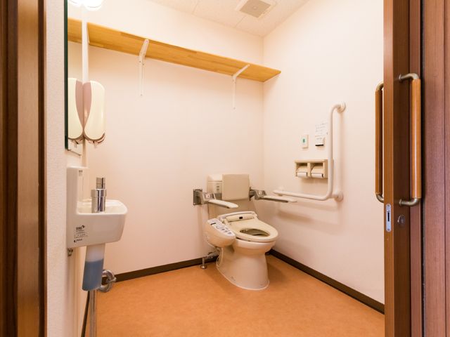 バリアフリー設計の洋室トイレ トイレ 手すりが備わり、広々とした洋式トイレです。ご利用の方々の快適さを考えた配慮が感じられます。