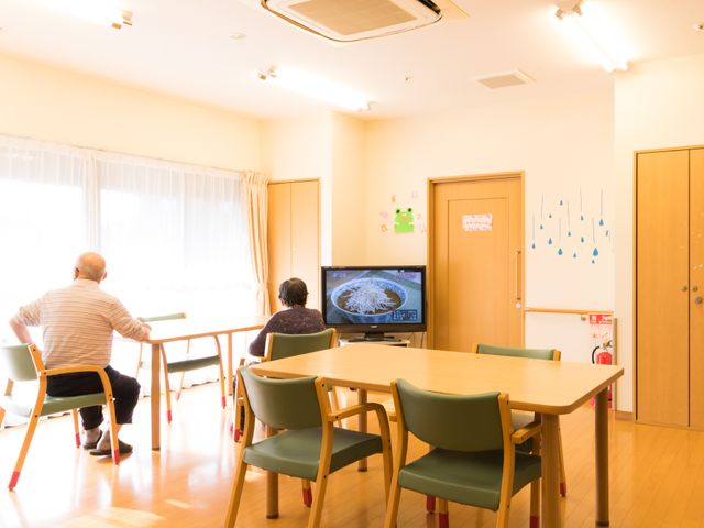 明るい共有スペースの様子 食堂 二人がテレビを観る暖かい雰囲気のラウンジです。ゆとりのスペースでコミュニケーションを楽しめる場所となっています。