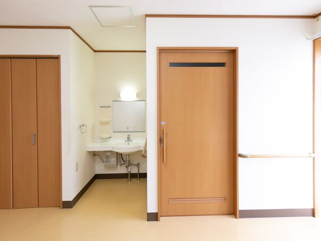 バリアフリーな居室の一角 居室 広々とした清潔感あふれる居室で、快適なプライベート空間が確保されています。手すりや低めの洗面台など、使いやすさに配慮が見られます。