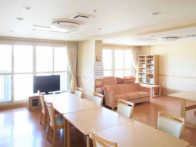 明るい共有スペースの居室 共有スペース 採光がたっぷりと差し込むリビングです。ゆったりとしたソファや、本棚が備え付けられ、くつろぎや交流の時間を提供しています。