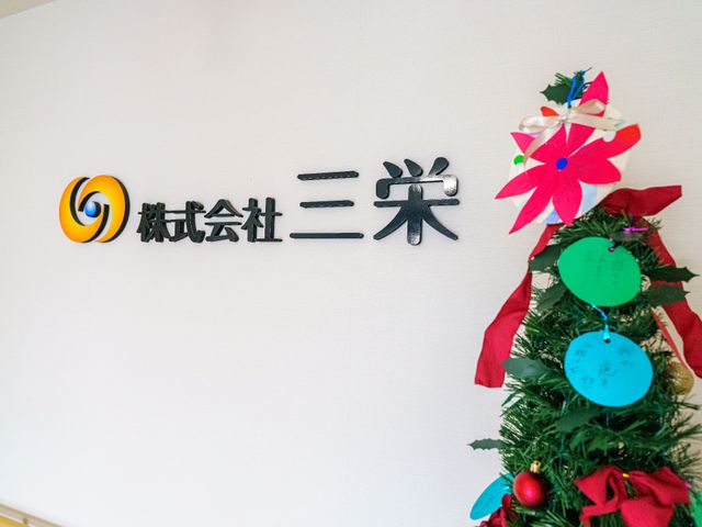 壁に掲示された看板と装飾 会社名 お出迎えする壁には、季節感あふれる装飾と共に名称が掲げられ、訪れる人々に温かな印象を与えます。