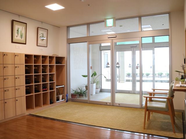 明るい玄関の様子 玄関 広々としたエントランスは木目調のインテリアで落ち着いた雰囲気です。明るい日差しを受ける窓からは、開放感溢れる空間をご覧いただけます。