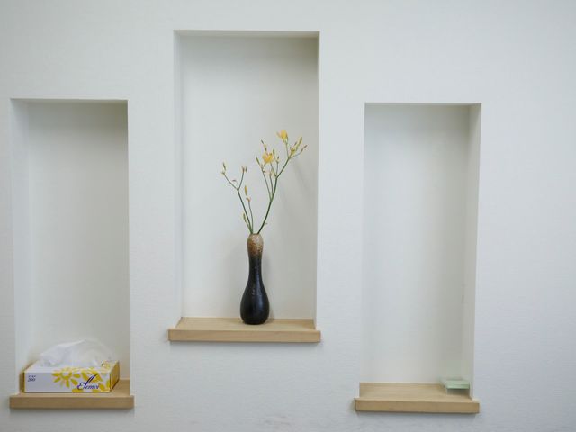 壁の花瓶とティッシュボックス 装飾品 シンプルで清潔感のある廊下に小さな飾り棚があり、心地よい空間を演出しています。働く環境の一端をご覧ください。