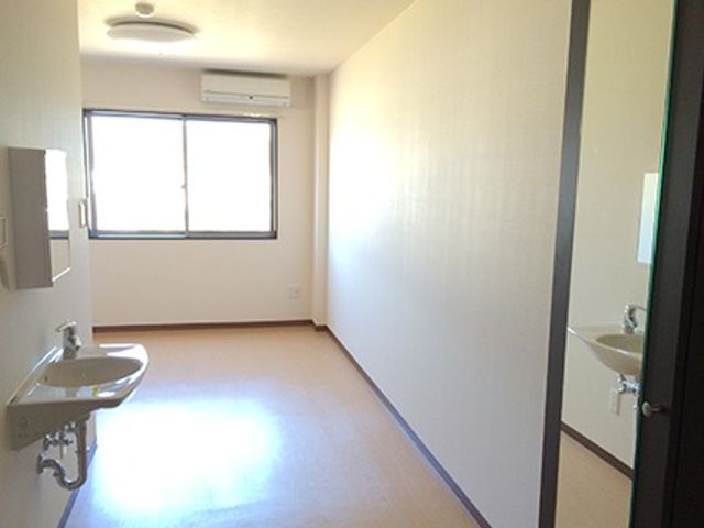 明るい室内の居室 居室 日当たりの良い個室で、ゆったりとくつろげる空間です。洗面台も完備しており、個人の生活に配慮した設計になっています。