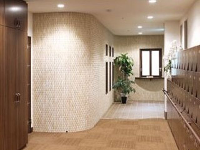 快適な廊下の様子 玄関 清潔感あふれる廊下は広々としており、ゆったりとした歩行が可能です。壁面の郵便ポストや緑の植物が、心地よい日常を提供します。