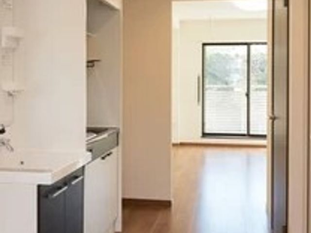 明るいキッチンと廊下 居室 清潔感のある居室のキッチンは、自炊を楽しむ空間として十分な機能を備えています。廊下の先には庭へと続く扉があり、開放感が感じられます。