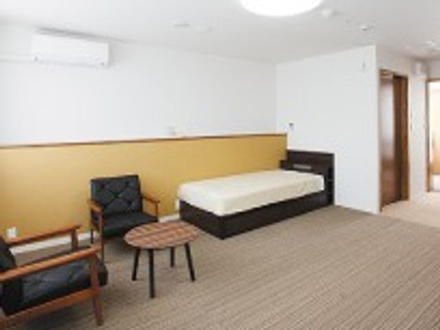 快適な居室 居室 明るく広々とした居室で、リラックスできる環境が整っています。ベッドと椅子が配置されています。