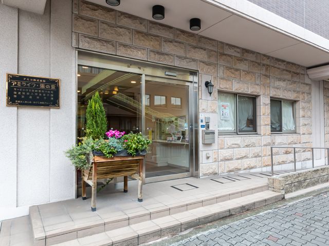 エントランスの明るい風景 玄関 心地よい明るさのあるエントランスは、来訪者を暖かく迎えます。玄関口には植物が飾られ、訪れる人々に安らぎを提供しています。
